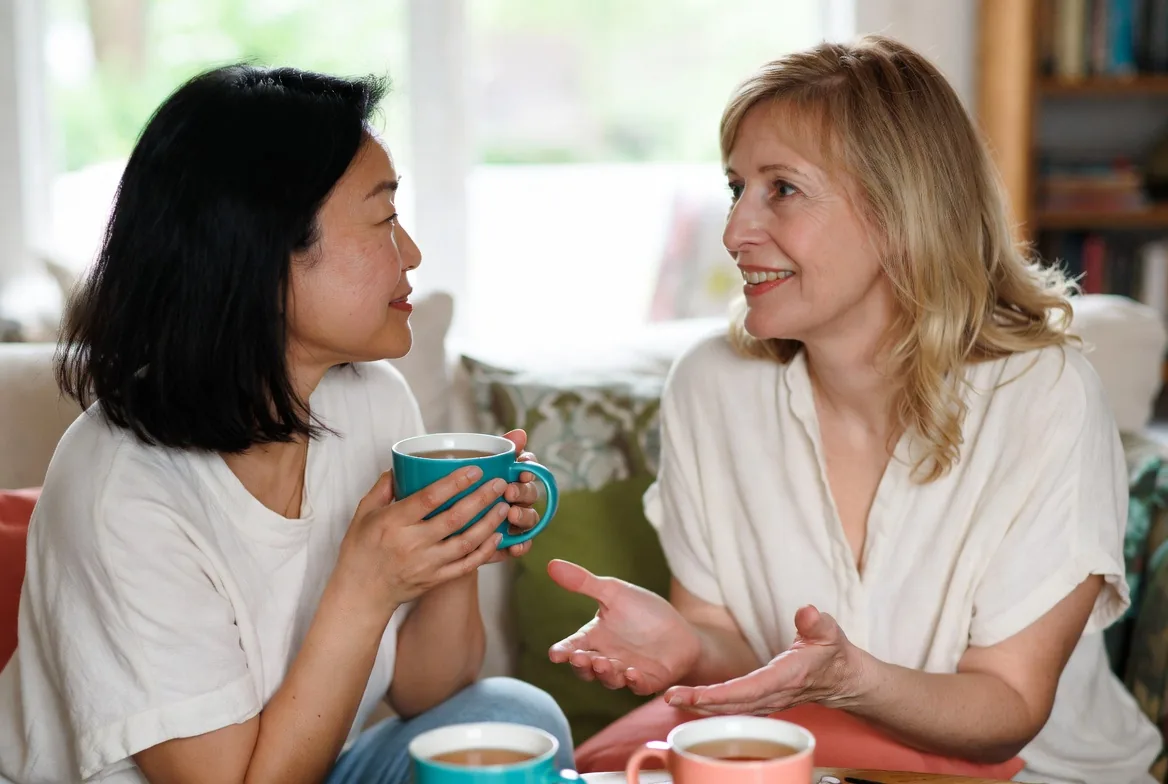 Two women talking warmly over tea, breaking the isolation of bladder leaks
