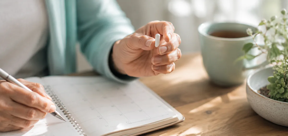 Hands marking a wellness calendar while planning a daily FemiCore supplement routine