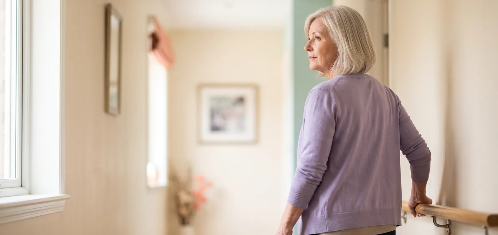 Arthritis and bladder leaks: woman steadying herself on a hallway handrail at home