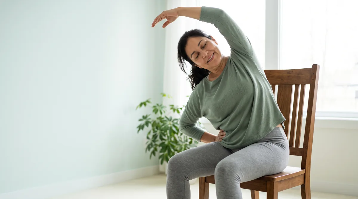 Woman in her fifties doing a gentle seated stretch at home